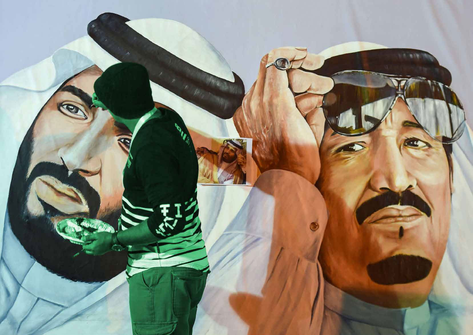 فنان سعودي يضع اللمسات الأخيرة على جدارية للملك سلمان بن عبدالعزيز، وولي عهده، خلال مهرجان الثقافة والتراث الثاني والثلاثين بالرياض في 17 فبراير الماضي